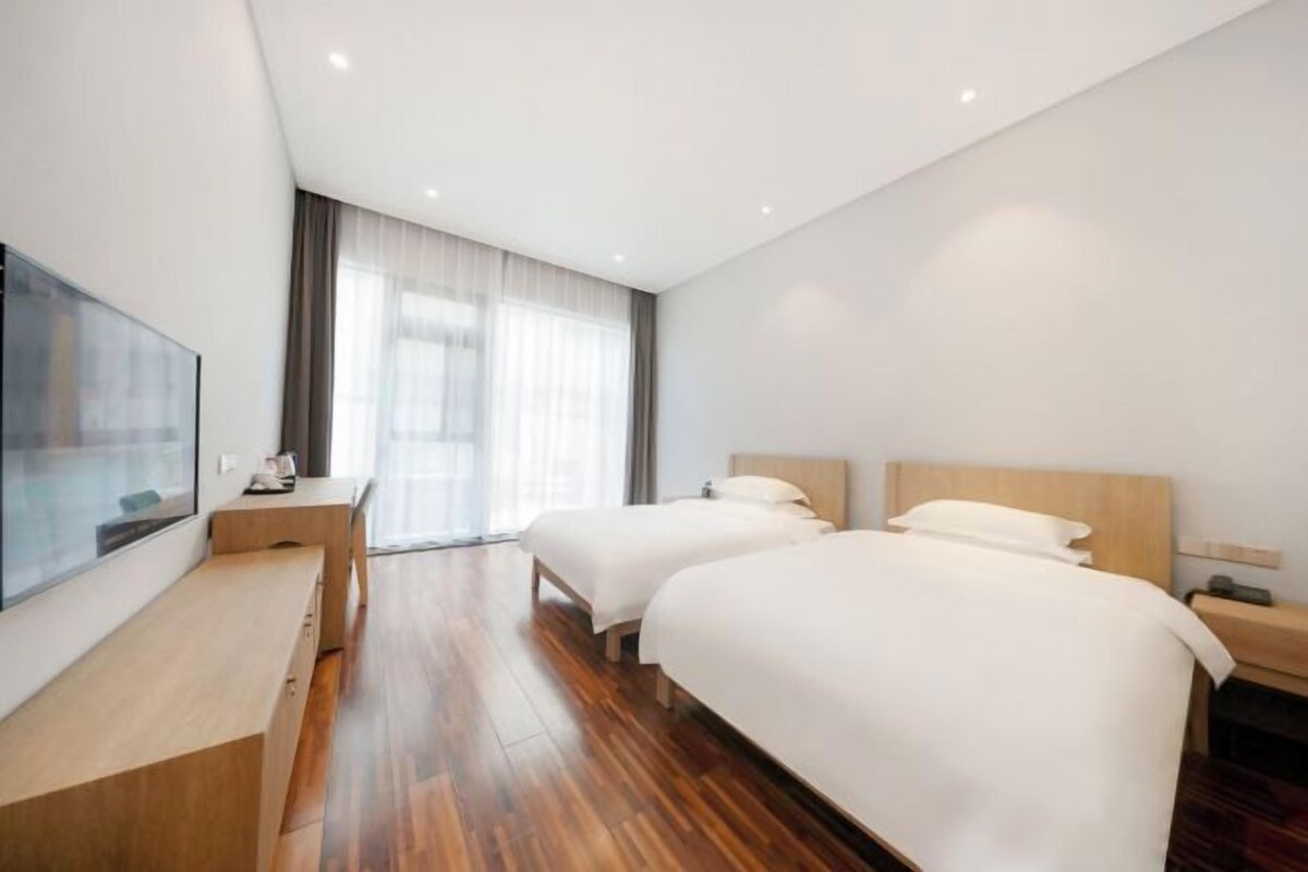 Habitació d'hotel amb dos llits, una taula de treball i una televisió.