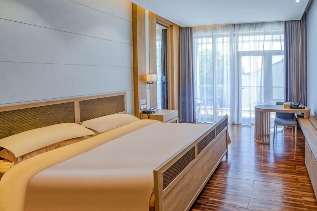 Una habitació d'hotel amb un llit gran, un escriptori i una cadira.