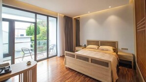 Quarto moderno com uma cama grande, uma escrivaninha e uma varanda com móveis de exterior.