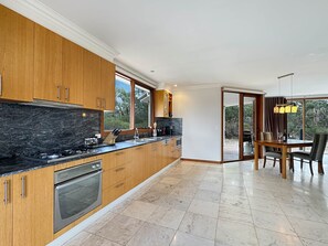 A modern kitchen with wooden cabinets, a black countertop, and a built-in oven.