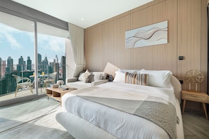 Un dormitorio moderno con una cama grande, un sofá, una mesita de centro y vistas a la ciudad.