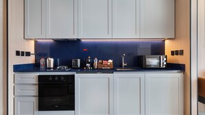 A modern kitchen with white cabinets, a black oven, a microwave, and a coffee bar. - High Floor Luxury Burj Khalifa & Canal View Studio (Dubai)