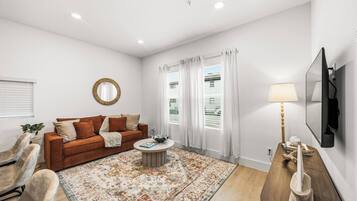 A modern living room with a sofa, coffee table, and a TV mounted on the wall.