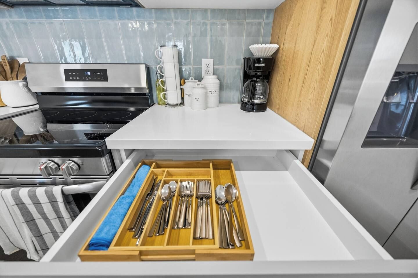 Una cucina con piano cottura in acciaio inossidabile, macchina del caffè e organizer a cassetti per utensili.