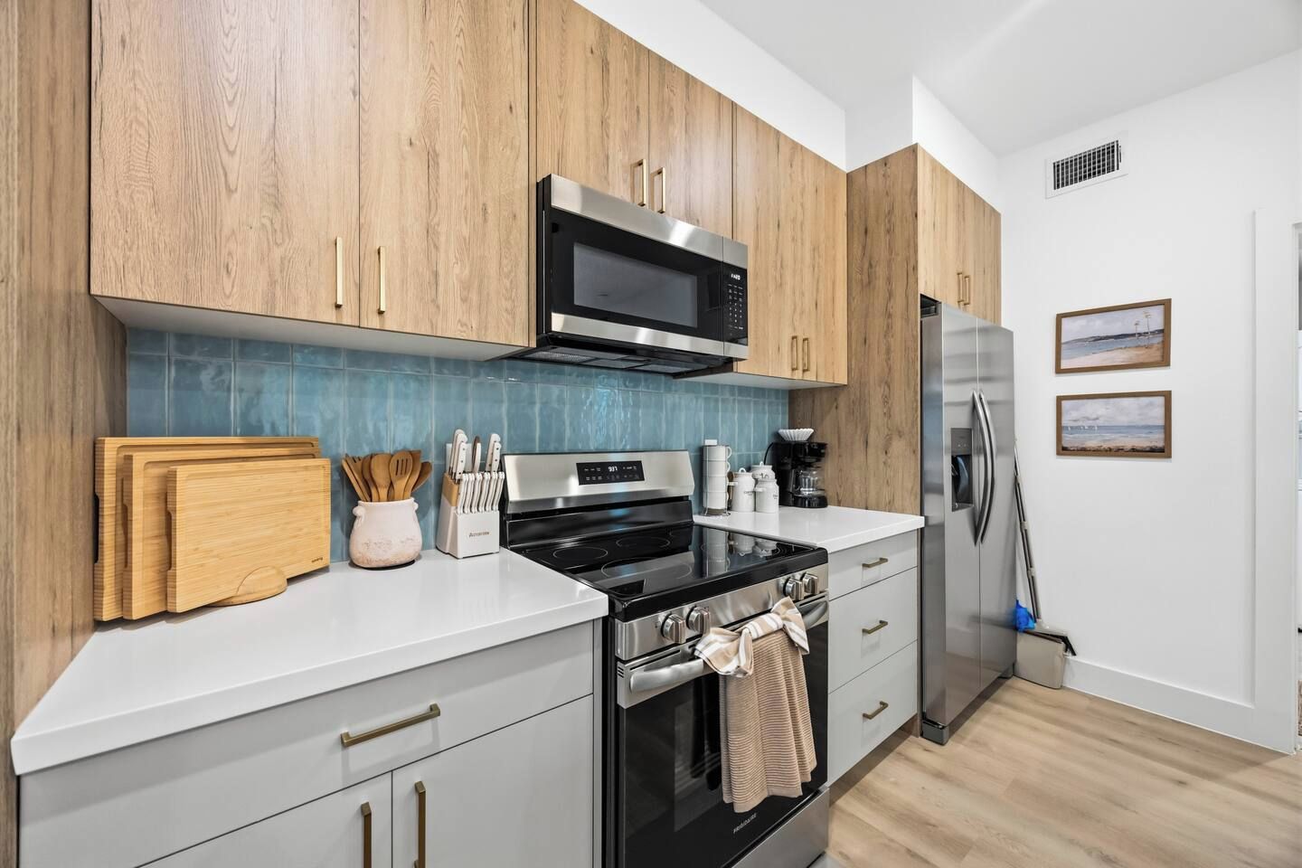 Una cocina moderna con armarios de madera, un microondas de acero inoxidable, una estufa negra y un refrigerador.