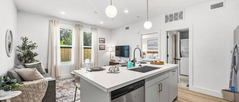 A modern kitchen with a central island, built-in dishwasher, and a dining area with a table and chairs.