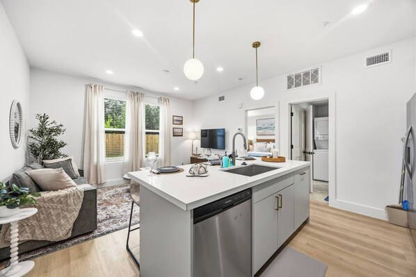A modern kitchen with a central island, built-in dishwasher, and a dining area with a table and chairs.