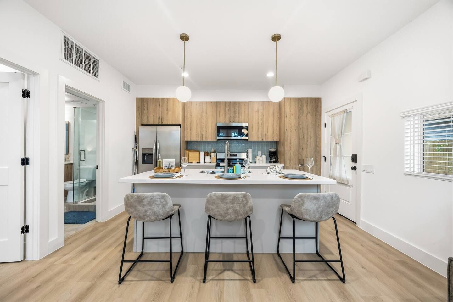 Une cuisine moderne dotée d’un îlot central, de tabourets de bar et de luminaires suspendus.