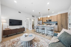 A modern living room with a flat-screen TV, a round coffee table, and a sofa.