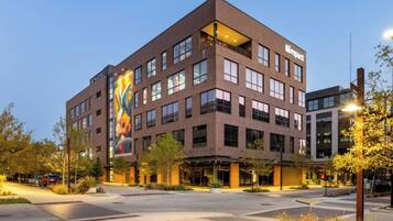 A multi-story building with a prominent 'Dine In' sign, large windows, and a landscaped courtyard.