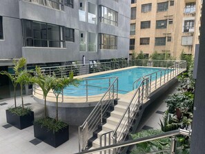 A rooftop pool with a metal railing, surrounded by potted plants and a staircase leading to an upper level. - Urban n modern unit just in the heart of Nairobi. (Nairobi)