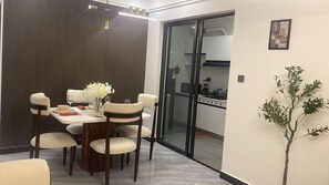 A dining area with a table set for four, a vase with flowers, and a view into the kitchen. - Urban n modern unit just in the heart of Nairobi. (Nairobi)