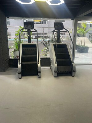Two treadmills in a gym with a view of a building and some plants outside. - Urban n modern unit just in the heart of Nairobi. (Nairobi)