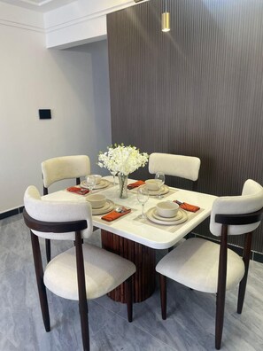 A dining area with a round table, four chairs, and a vase of flowers. - Urban n modern unit just in the heart of Nairobi. (Nairobi)
