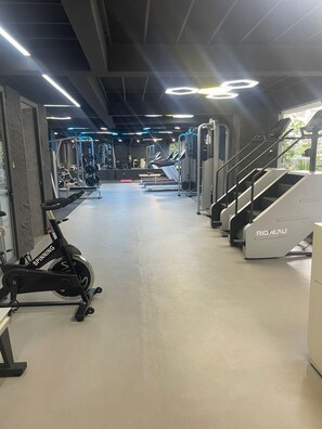 Ett gym med konditionsmaskiner, styrketräningsmaskiner och en trappmaskin.