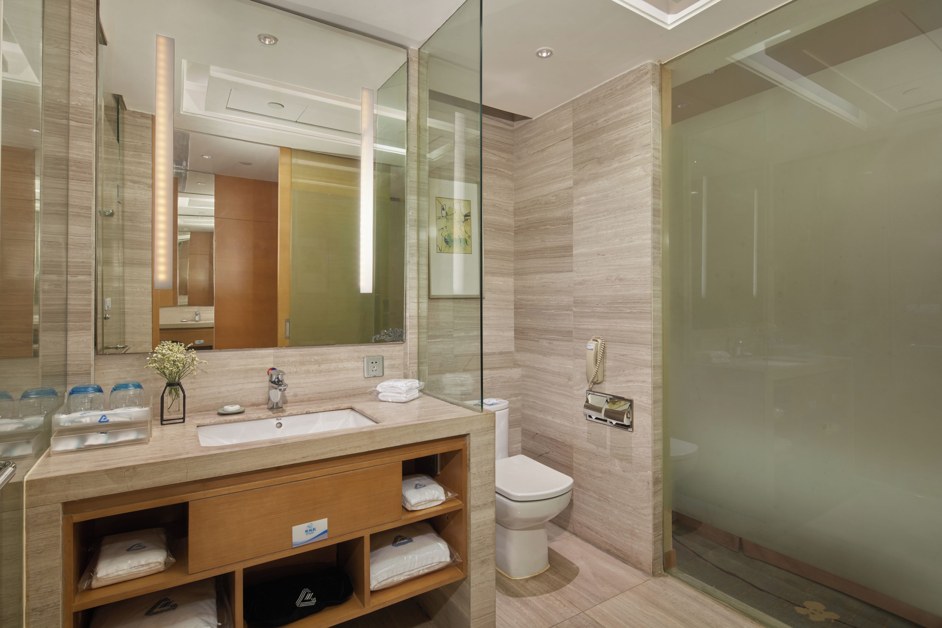 Un baño moderno con cabina de ducha de vidrio, tocador con lavabo y espejo, y un inodoro.