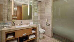 Un baño moderno con cabina de ducha de vidrio, tocador con lavabo y espejo, y un inodoro.