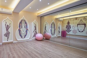 A room with a wooden floor, mirrored walls, and decorative wall art.