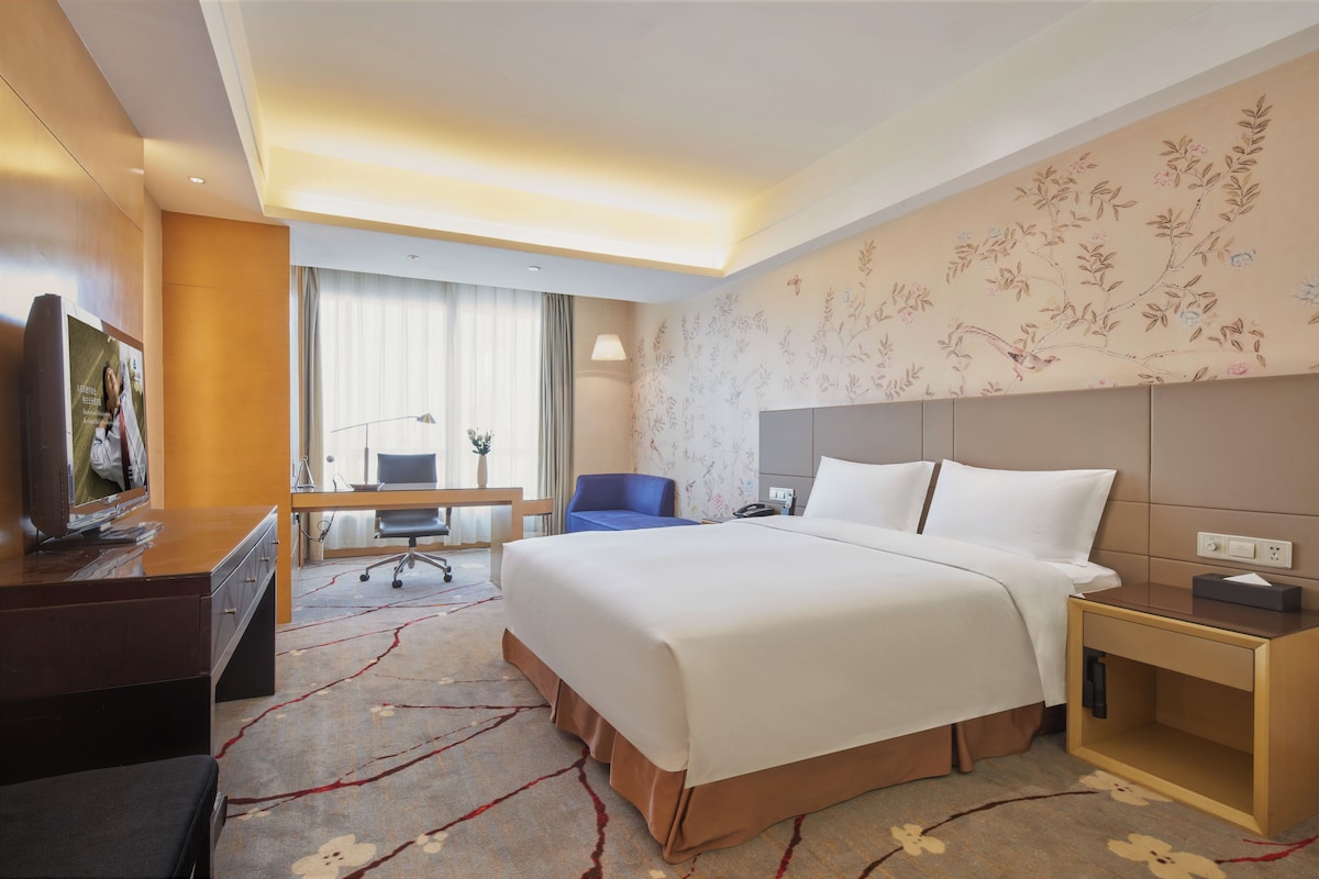 Una habitación de hotel con cama, escritorio, silla y televisor.