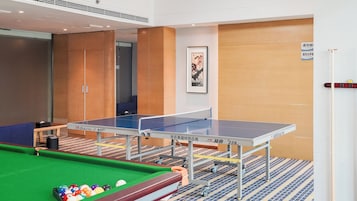 Una mesa de ping pong con mesa de billar al frente, una obra de arte enmarcada en la pared y una puerta con un letrero.