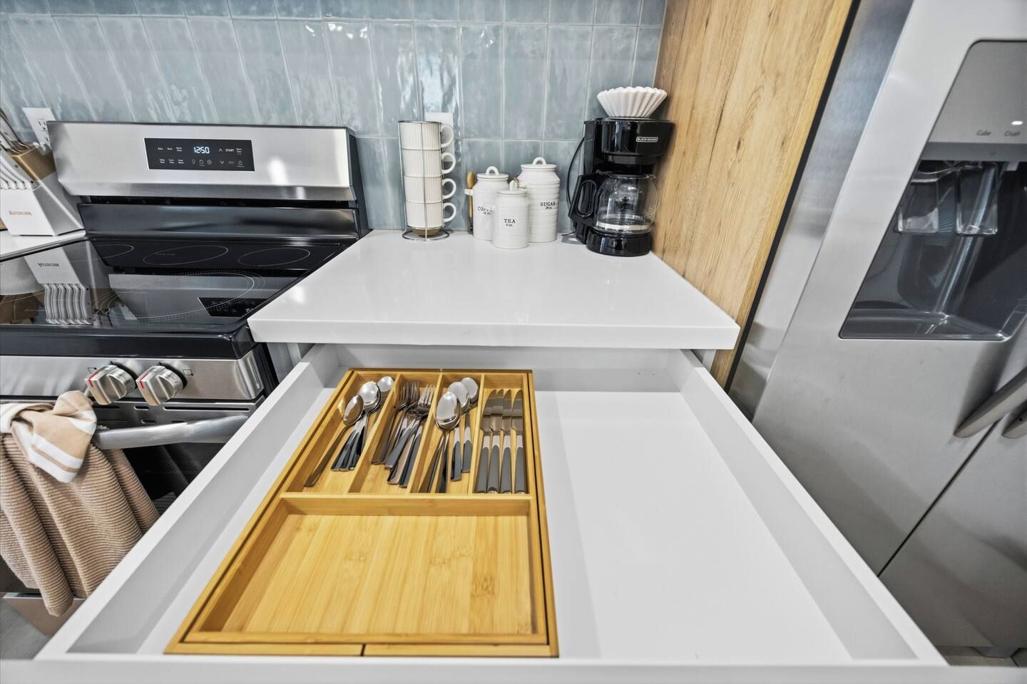 Una cucina con piano cottura integrato, una macchina da caffè e un organizer a cassetti per utensili.