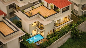 Um hotel com vários andares, piscina no terraço, varandas e um jardim bem cuidado.