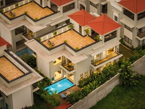 A multi-story hotel with a rooftop pool, balconies, and a well-maintained garden. - Paddy Field View 5 Mins Drive to Beach  (Goa)