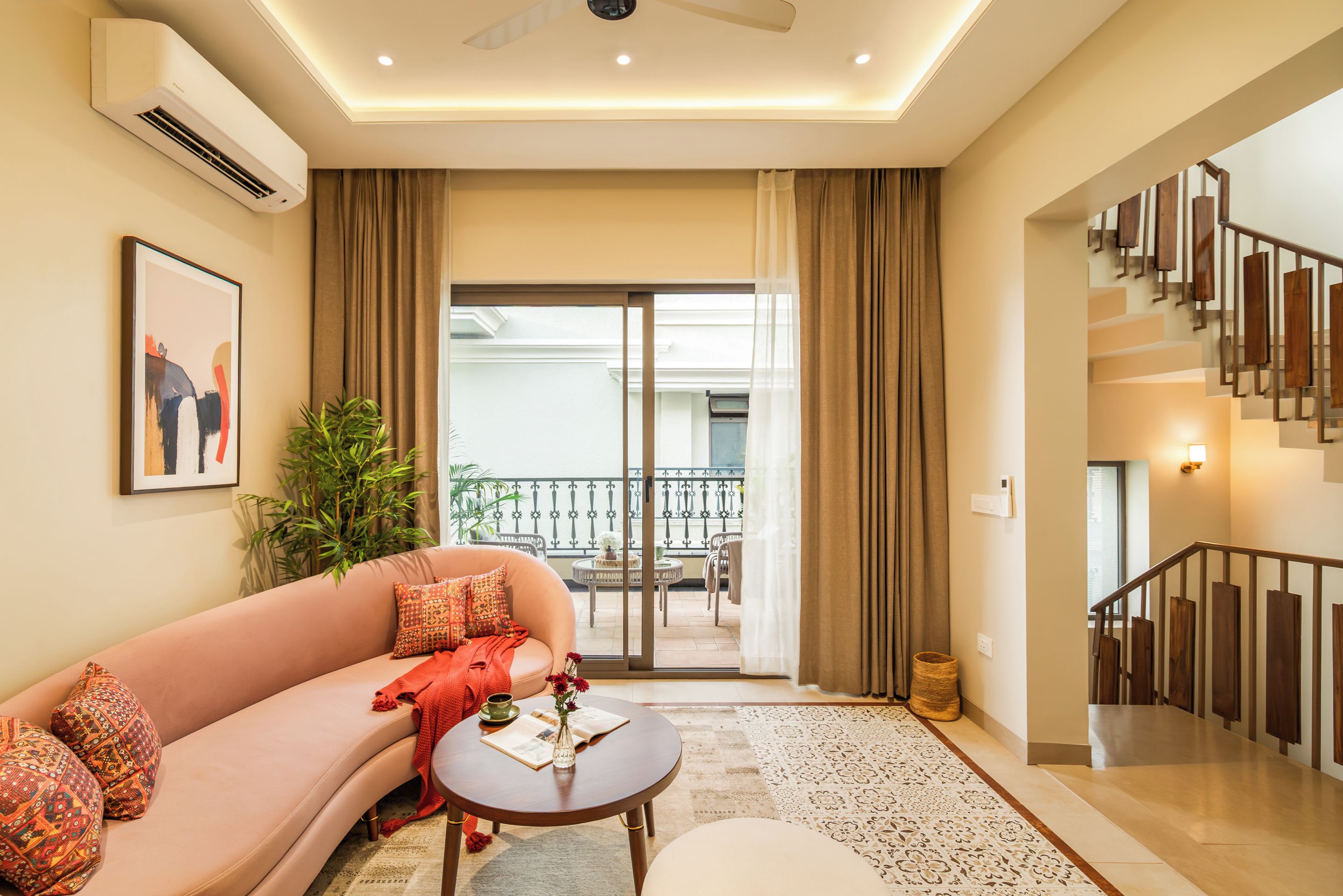 A modern living room with a sofa, a coffee table, and a view of a balcony.