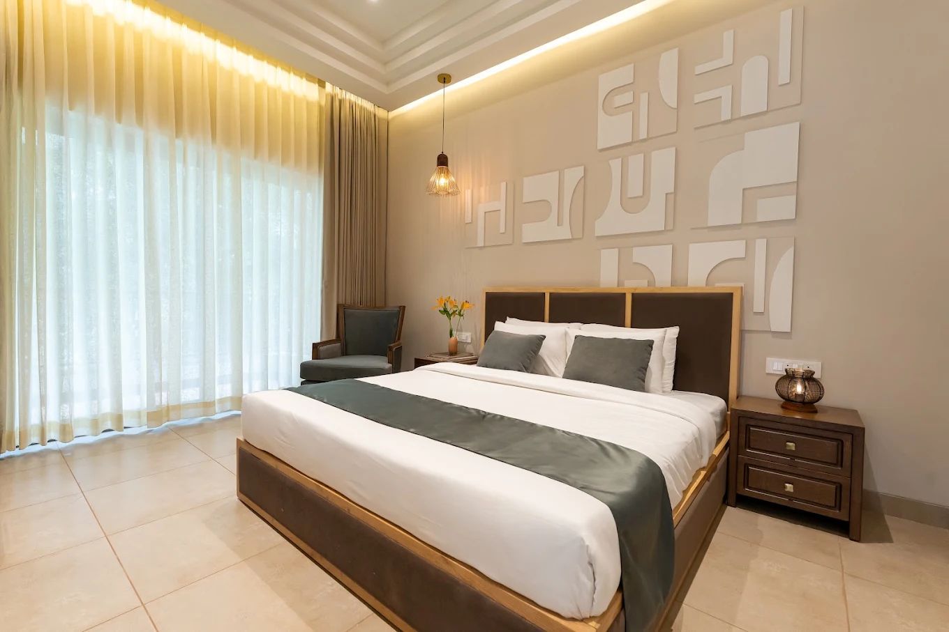 Un dormitorio moderno con una cama grande, una silla, una mesita de noche y una pared con diseños abstractos.