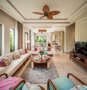 A spacious living area with a ceiling fan, a dining table, sofas, and a television. - Paddy Field View 5 Mins Drive to Beach  (Goa)
