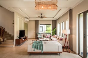 A modern living room with a sofa, television, and a ceiling fan.