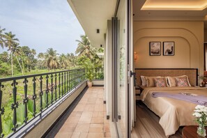 A bedroom with a large bed, a view of palm trees, and a balcony with a railing. - Paddy Field View 5 Mins Drive to Beach  (Goa)