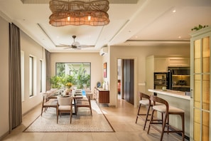 A modern dining area with a large window, a ceiling fan, and a kitchen with a built-in refrigerator.