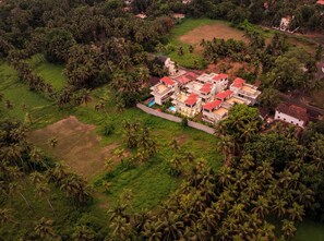 An aerial view of a residential area with multiple houses surrounded by lush greenery and palm trees.