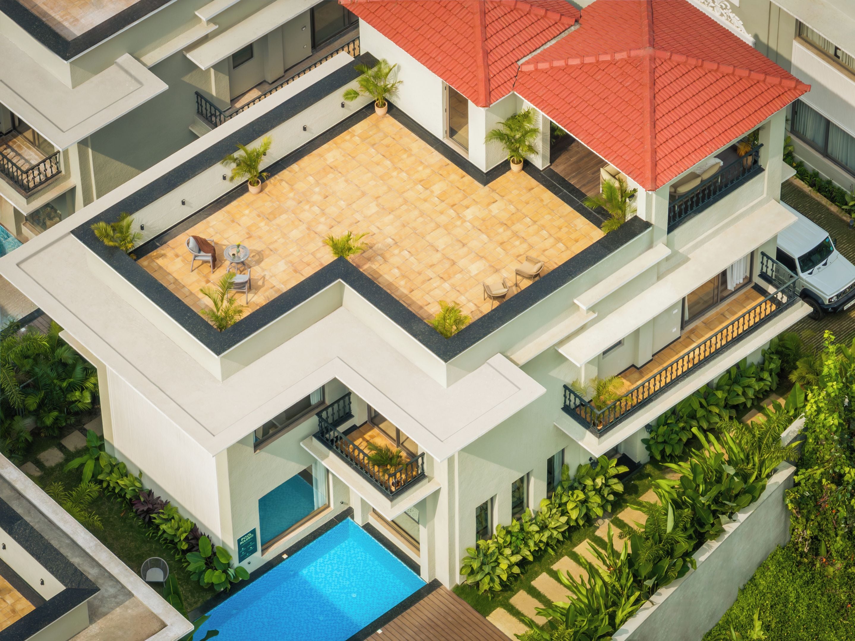 Um edifício residencial de vários andares com terraço no telhado, piscina e telhado de telhas vermelhas.