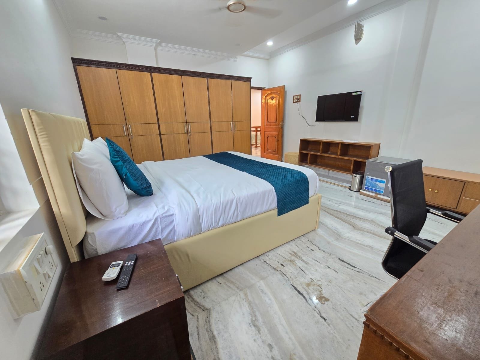 Una habitación de hotel con cama, escritorio, televisión y armario.
