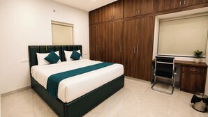 Ein Schlafzimmer mit Bett, Schrank, Schreibtisch und einer kleinen Topfpflanze.