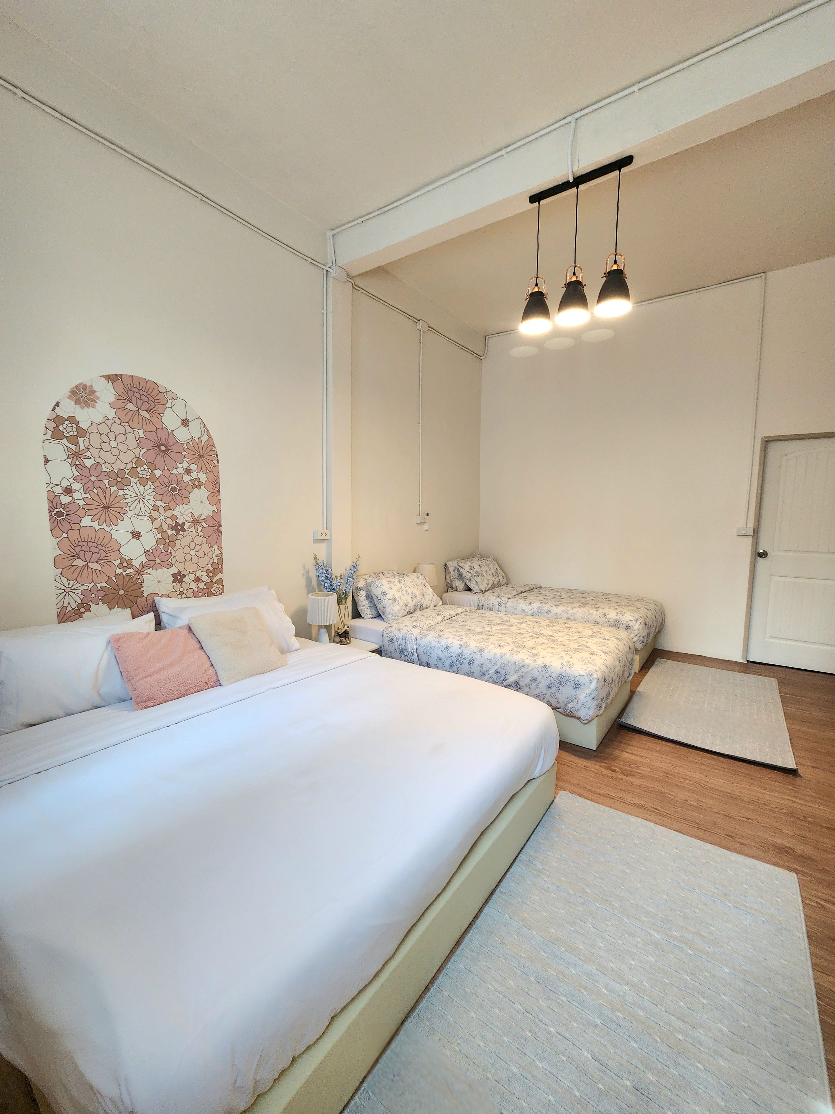 A bedroom with two beds, a nightstand, a lamp, and a decorative wall piece.