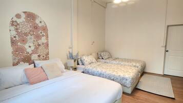 A bedroom with two beds, a nightstand, a lamp, and a decorative wall piece.