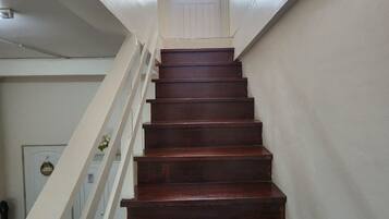 A wooden staircase with white railings leading to a door with a window.