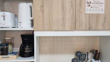 A kitchen with a coffee maker, a scale, and various kitchen utensils.