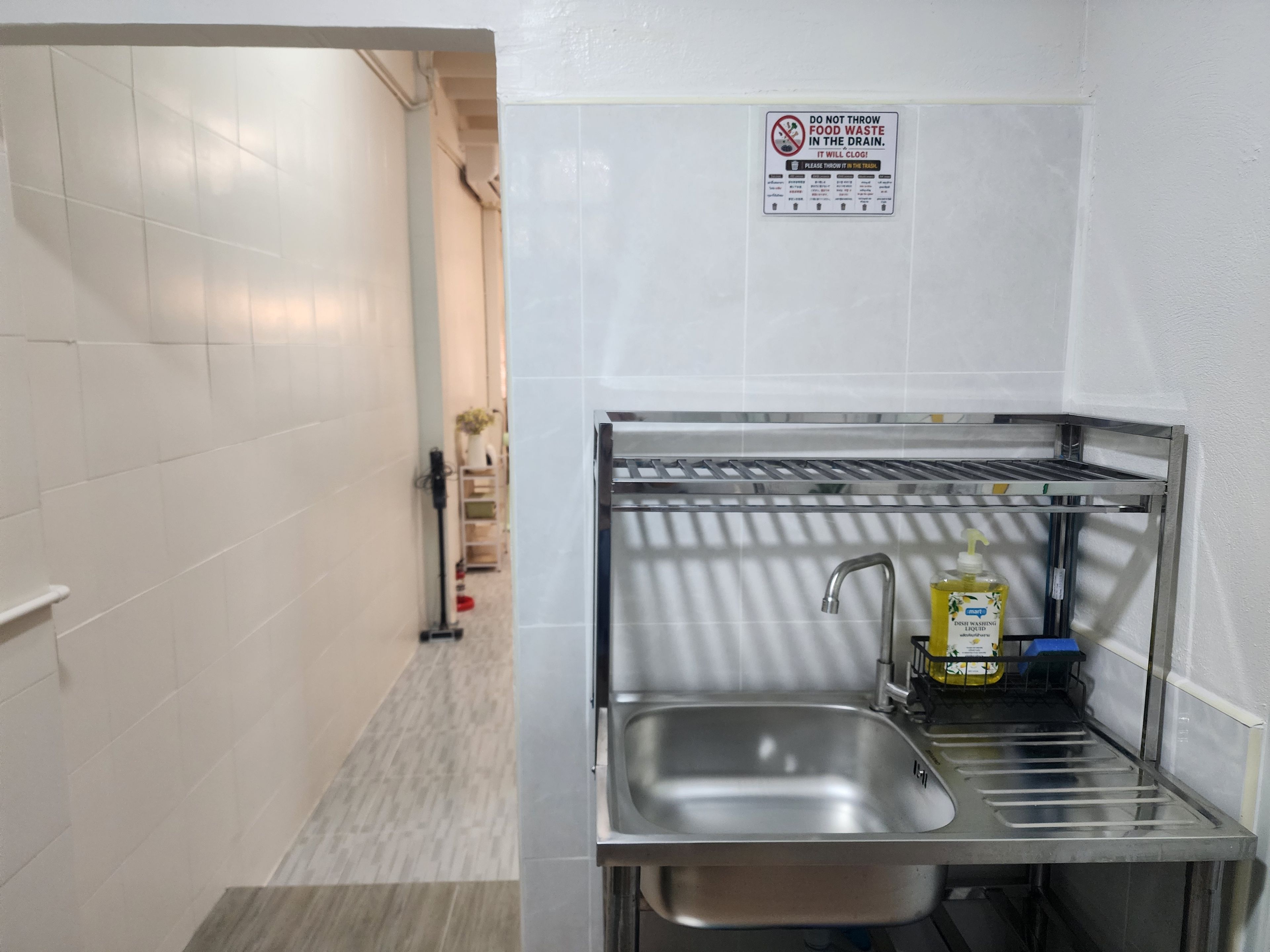 A small kitchen area with a stainless steel sink, a dish rack, and a bottle of dishwashing liquid.
