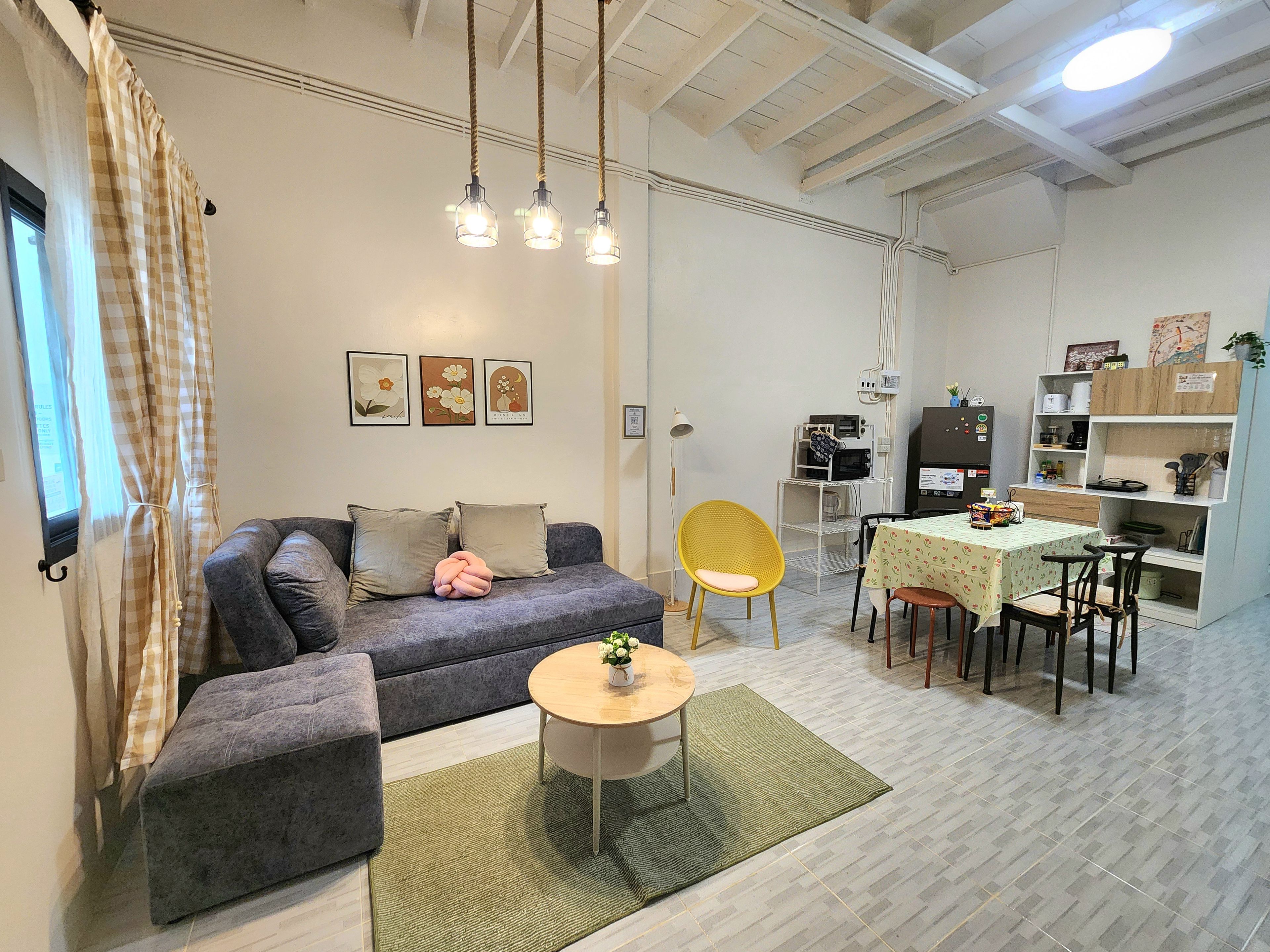 A modern living space with a sofa, a dining table, and a kitchen area.