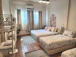 Een hotelkamer met een bed, twee nachtkastjes, een stoel, een kledingkast, een hangroede en een raam met gordijnen.