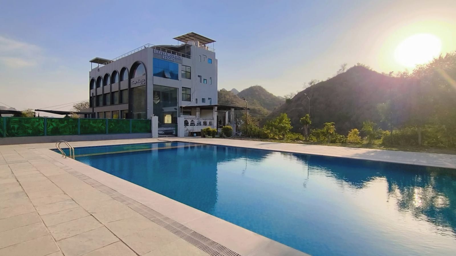 Un complexe hôtelier doté d’une piscine, d’un immeuble à plusieurs étages et situé dans un cadre montagneux.