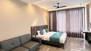 Una habitación de hotel moderna con cama, sofá, escritorio y ventilador de techo.
