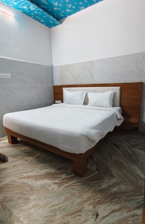 A bedroom with a bed, wooden headboard, marble wall, and a blue ceiling. - Bhavya Mountain Resort Udaipur (Udaipur)