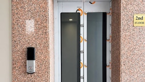 Un ascensor con revestimiento de acero inoxidable, un panel de control digital y un cartel que indica el segundo piso.