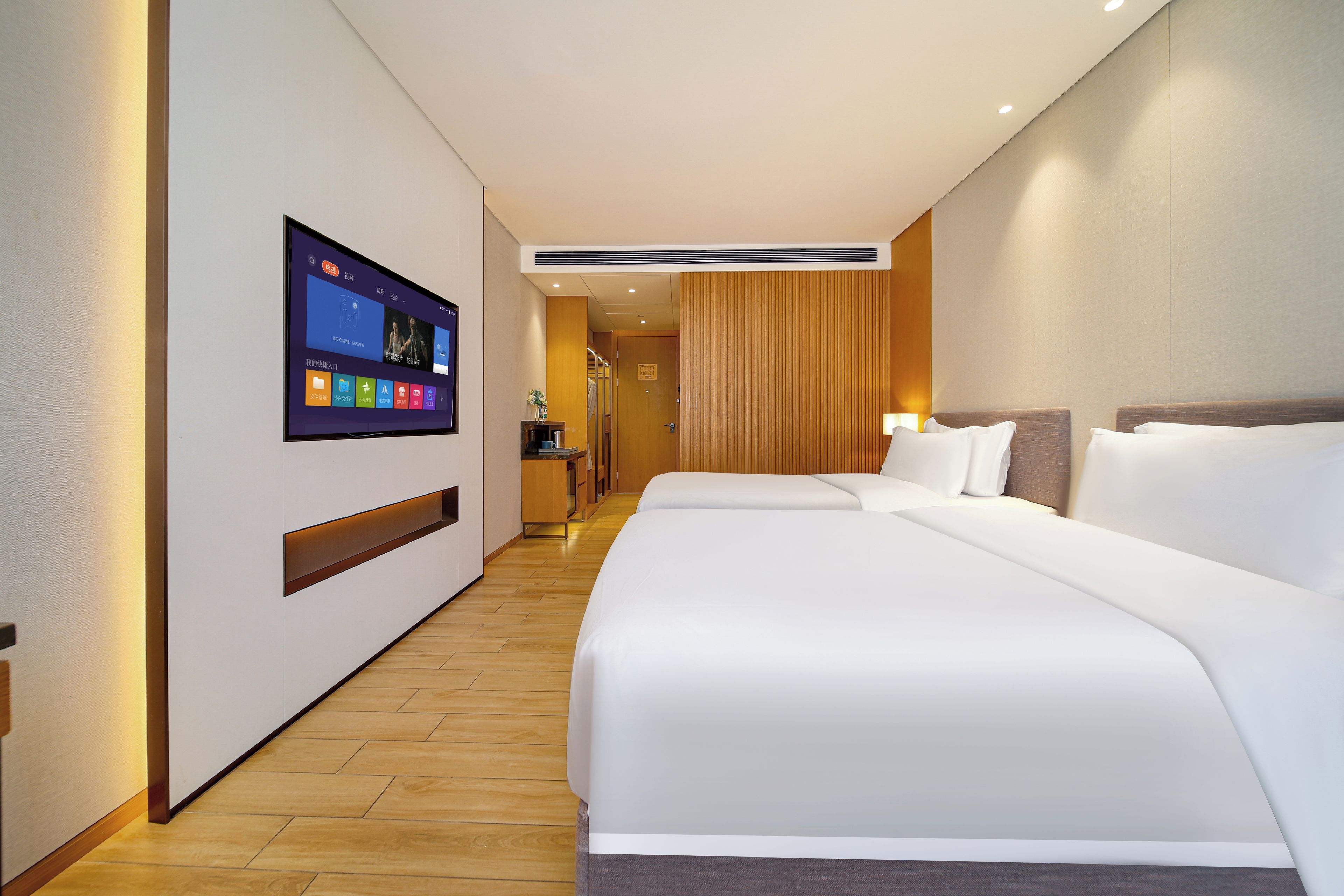 Quarto de hotel com uma cama grande, televisão fixada na parede e piso de madeira.