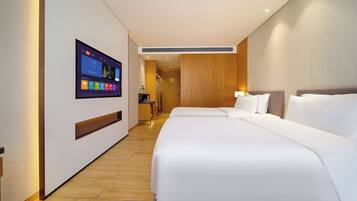 Quarto de hotel com uma cama grande, televisão fixada na parede e piso de madeira.